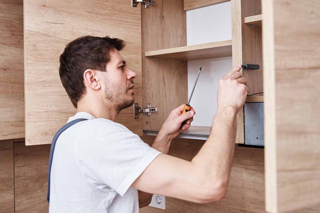Handyman repairing a wooden cabinet door